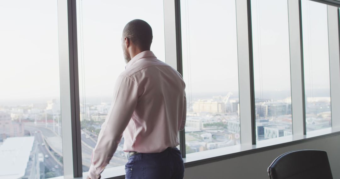 Businessman Overlooking City Through Office Window - Free Images, Stock Photos and Pictures on Pikwizard.com