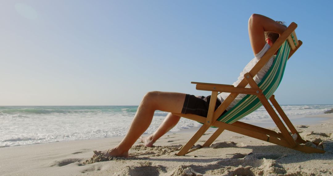 Man Relaxing on Sun Lounger by Tranquil Ocean Shoreline