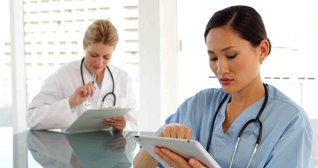 Medical workers sitting at desk using tablet at the hospital - Free Images, Stock Photos and Pictures on Pikwizard.com