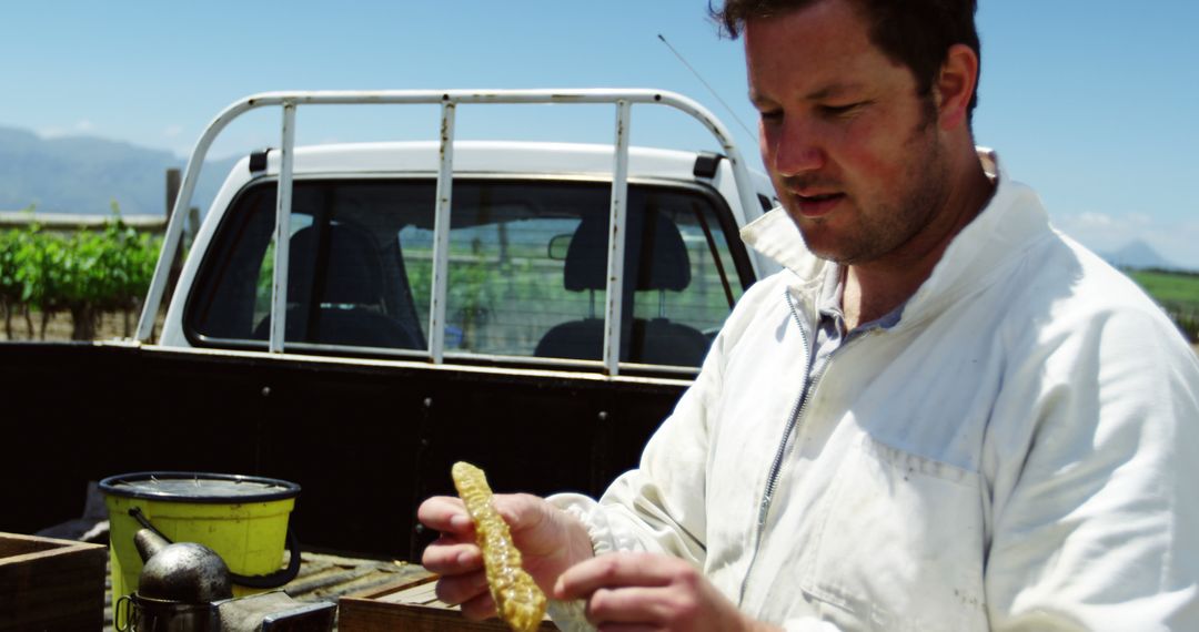 Beekeeper Inspecting Honeycomb on Farm Near Pickup Truck - Free Images, Stock Photos and Pictures on Pikwizard.com