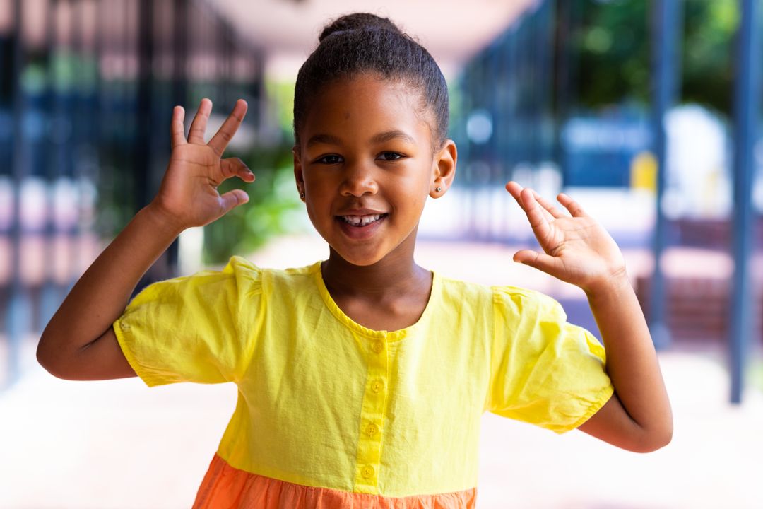 Happy African American Schoolgirl Smiling and Waving in School Corridor - Free Images, Stock Photos and Pictures on Pikwizard.com