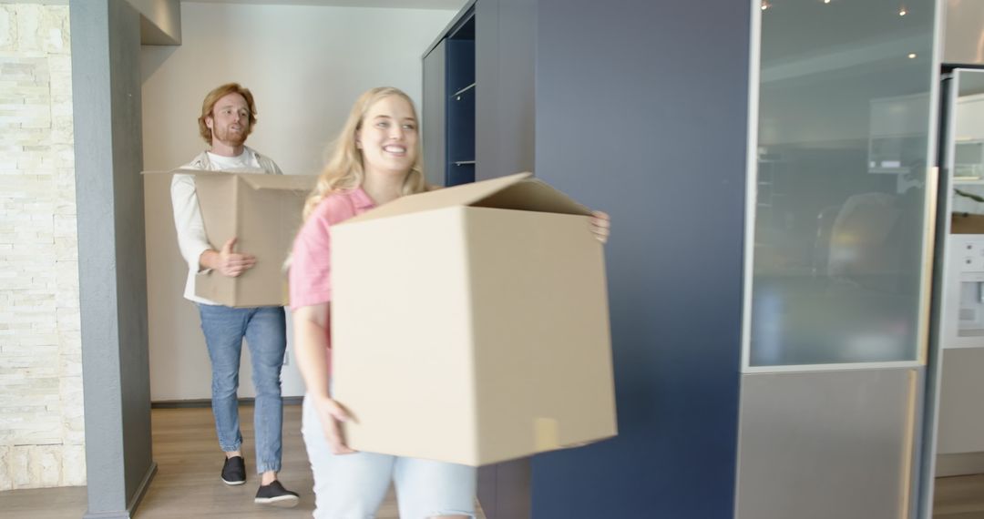 Joyful Couple Moving Boxes into New Home Kitchen
