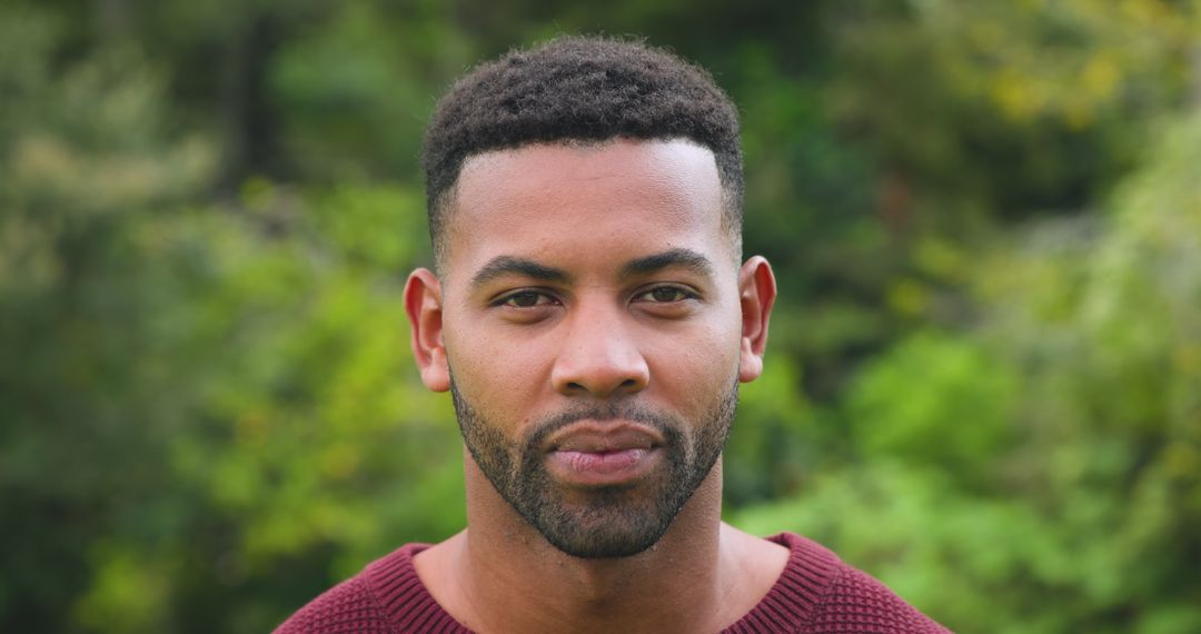 Contemplative Man in Park Wearing Burgundy Sweater