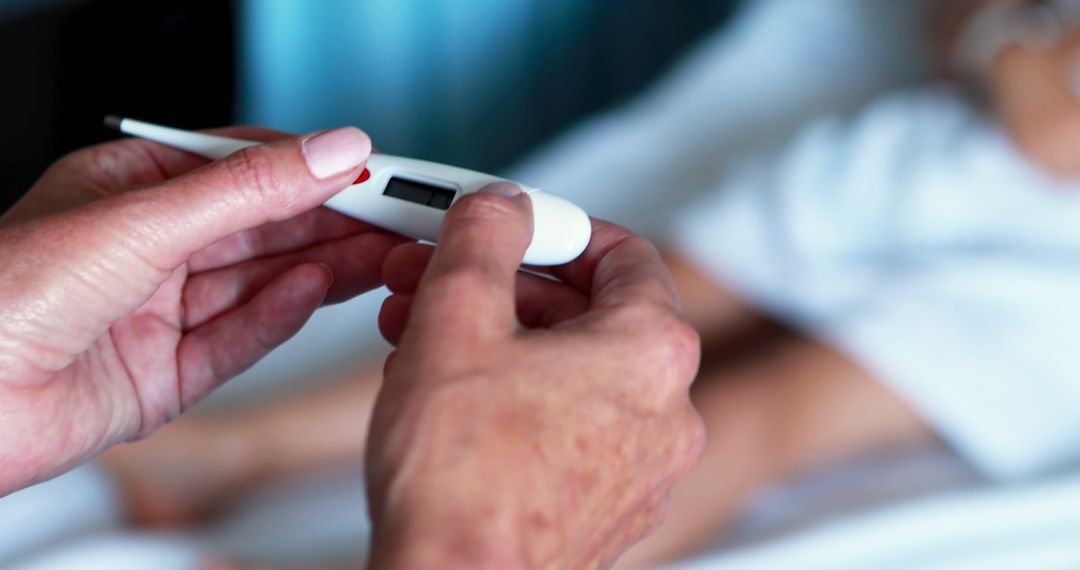 Hands Holding Digital Thermometer Next to Patient in Bed - Free Images, Stock Photos and Pictures on Pikwizard.com