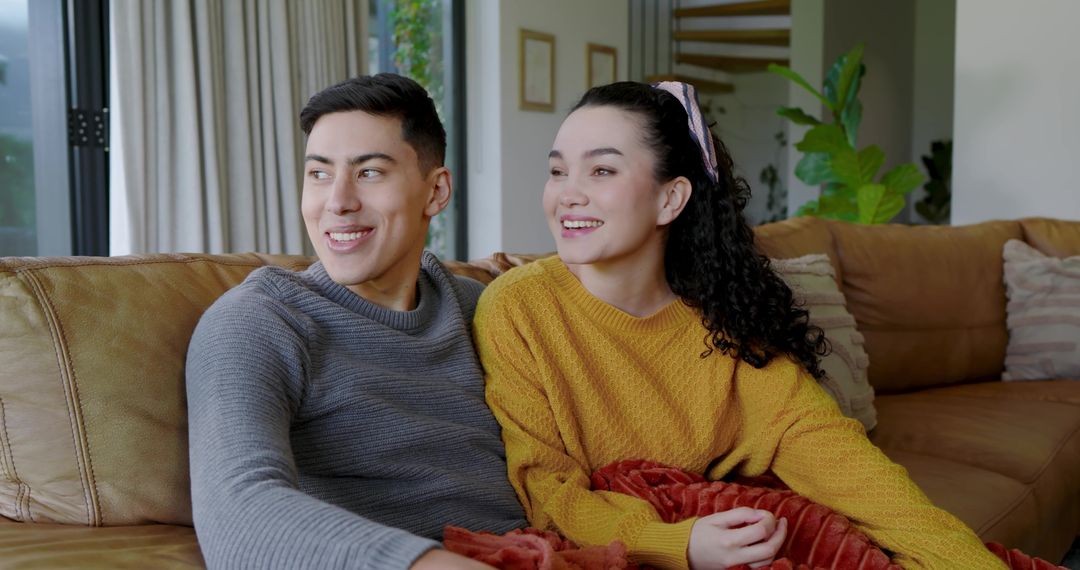 Smiling Couple Relaxing on Sofa with Cozy Blanket at Home