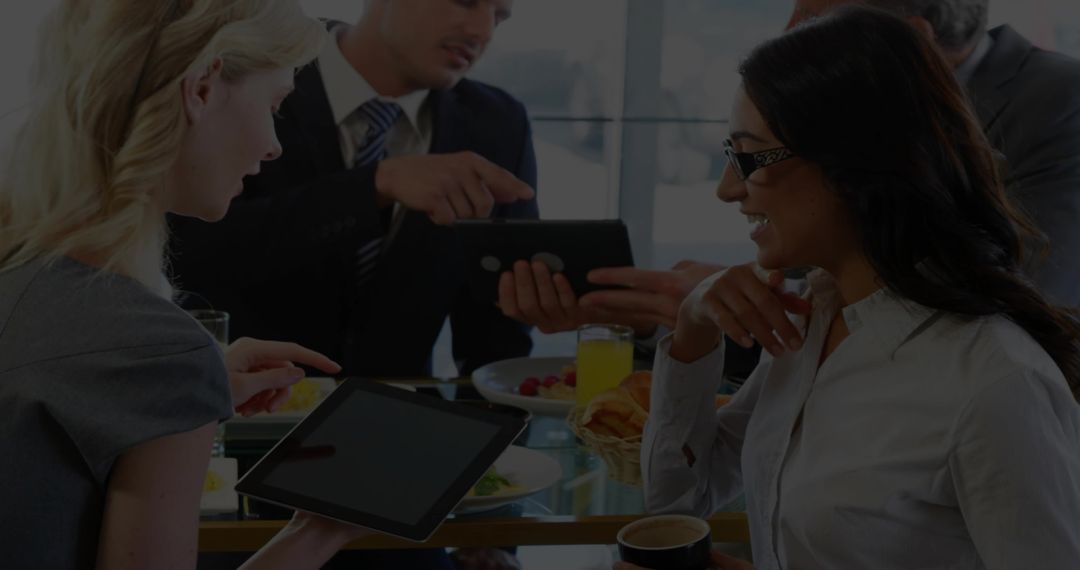 Business team collaborating over tablet during breakfast meeting in modern office lounge