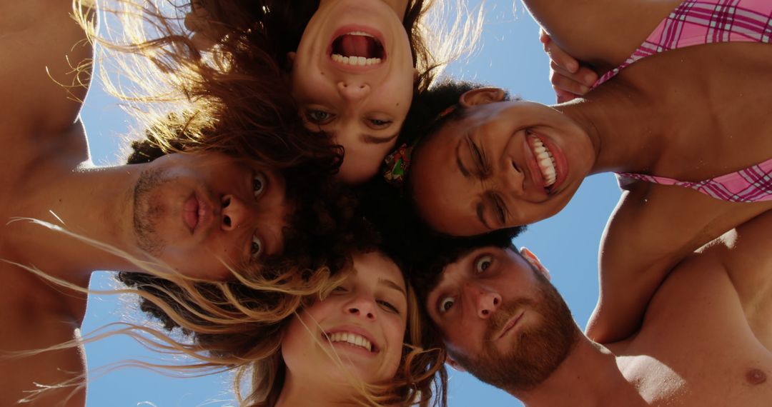 Low angle portrait of happy diverse friends making funny faces and embracing against sunny blue sky - Free Images, Stock Photos and Pictures on Pikwizard.com