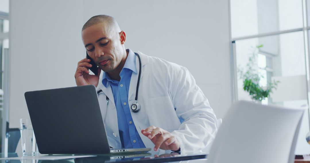 Doctor Working on Laptop and Talking on Phone in Office - Free Images, Stock Photos and Pictures on Pikwizard.com