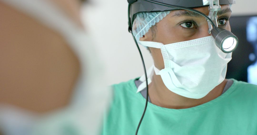 Focused Surgeon Considers Procedure with Headlamp in Operating Room - Free Images, Stock Photos and Pictures on Pikwizard.com