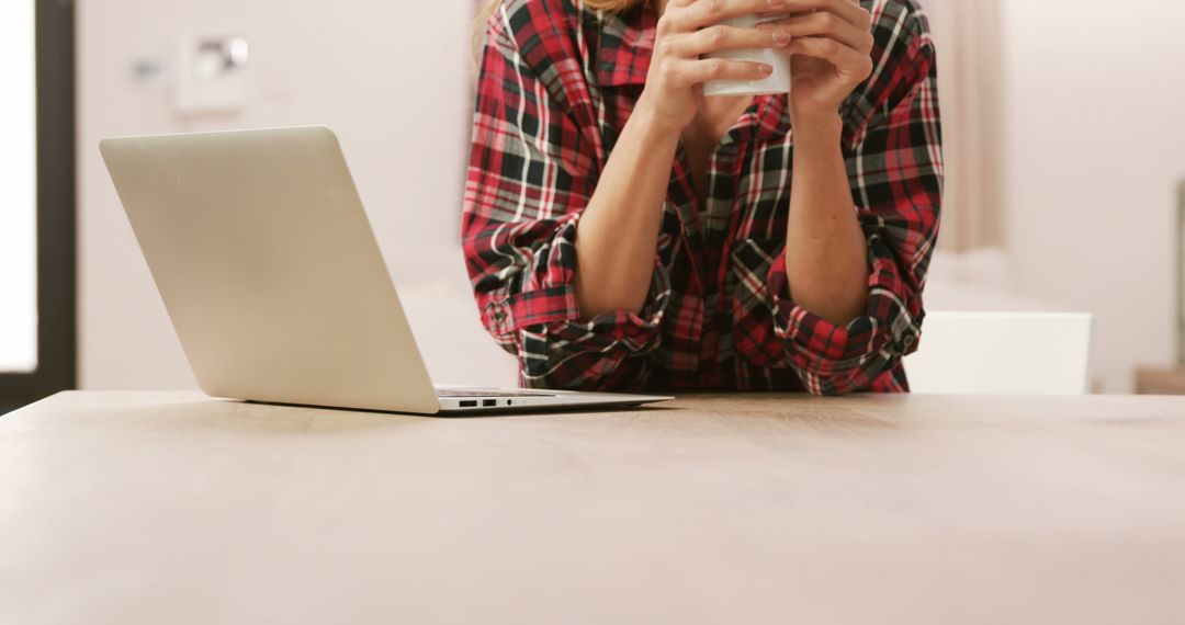 Woman Holding Coffee and Working From Home with Laptop - Free Images, Stock Photos and Pictures on Pikwizard.com