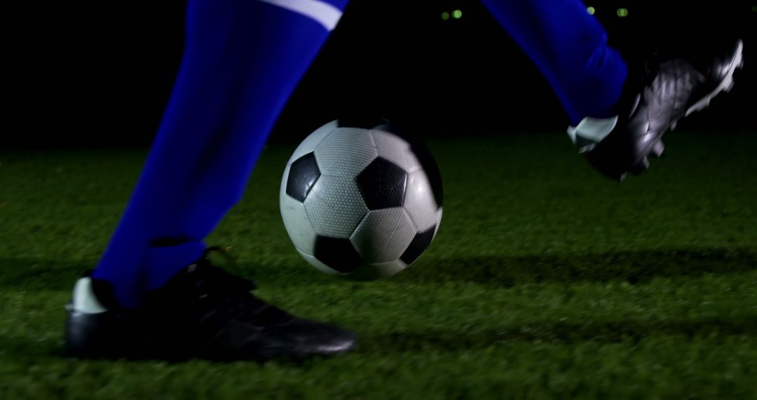 A soccer player in blue sportswear is about to kick a football during a night game, with copy space - Free Images, Stock Photos and Pictures on Pikwizard.com