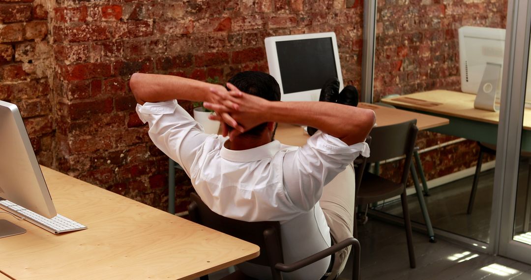 Man Relaxing in Modern Office with Exposed Brick Wall - Free Images, Stock Photos and Pictures on Pikwizard.com