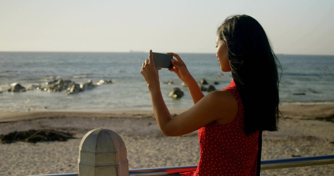 Woman Capturing Ocean View on Smartphone at Seaside Promenade