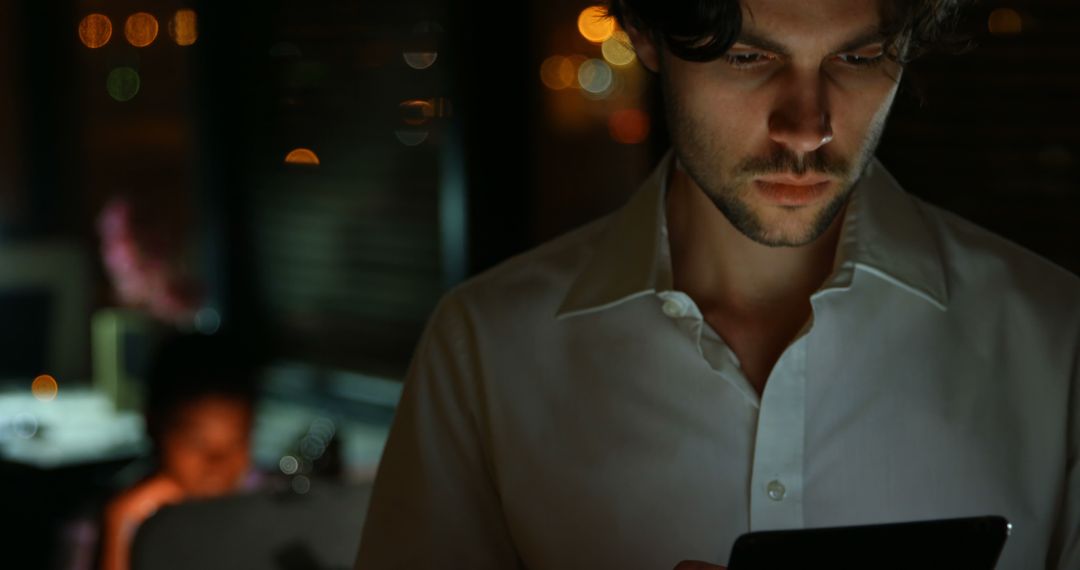 Focused Man Working Late on Digital Tablet in Dimly Lit Office - Free Images, Stock Photos and Pictures on Pikwizard.com