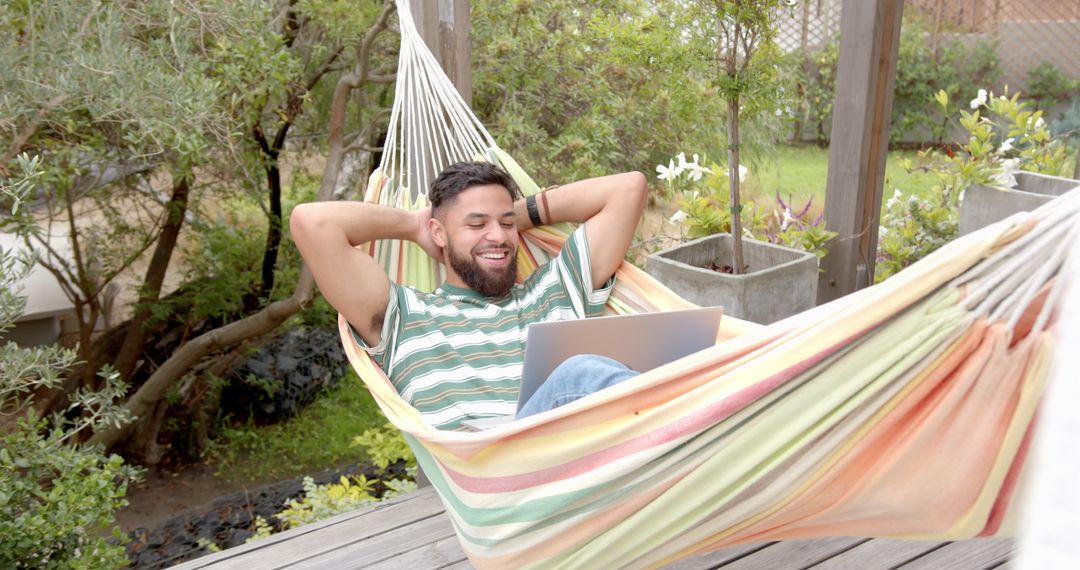 Man Relaxing in Garden Hammock With Laptop Enjoying Leisure Time Outdoors