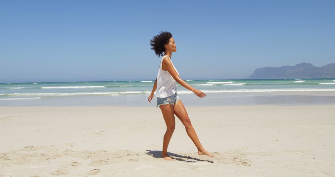 Young Woman Enjoying Walk on Sunny Beach - Free Images, Stock Photos and Pictures on Pikwizard.com