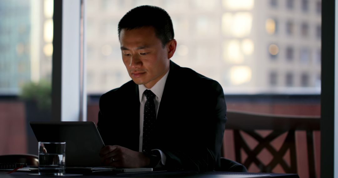 Focused Businessman Working on Tablet in Office at Night - Free Images, Stock Photos and Pictures on Pikwizard.com