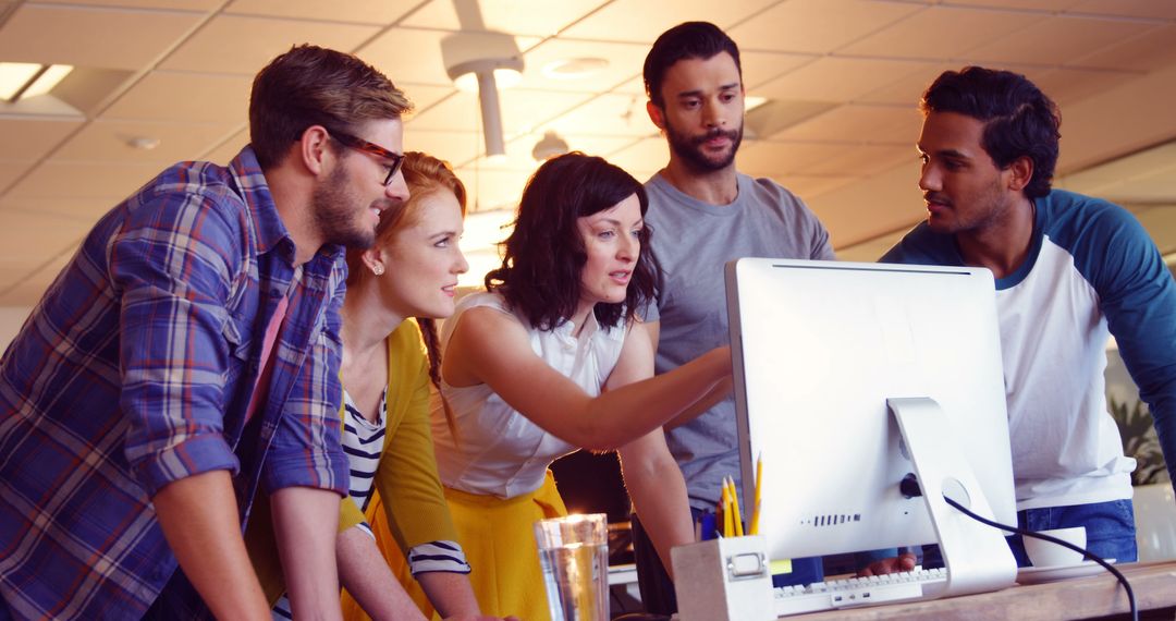 Diverse Team Collaborating Around Computer in Modern Office