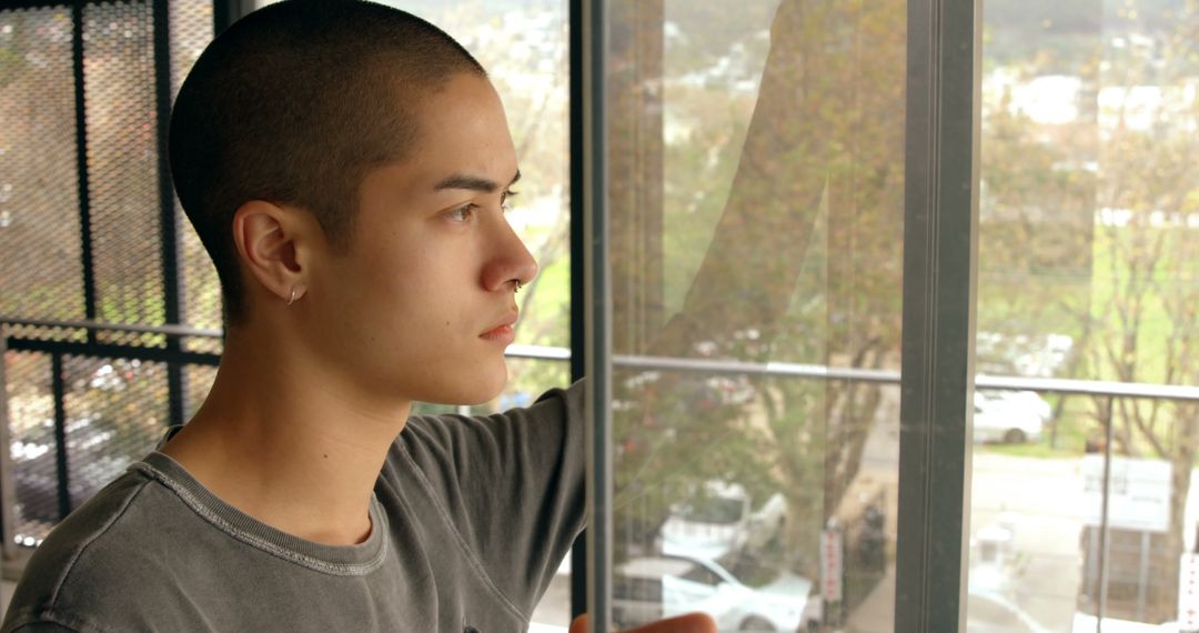 Pensive Young Man Looking Out Window, Urban Background - Free Images, Stock Photos and Pictures on Pikwizard.com