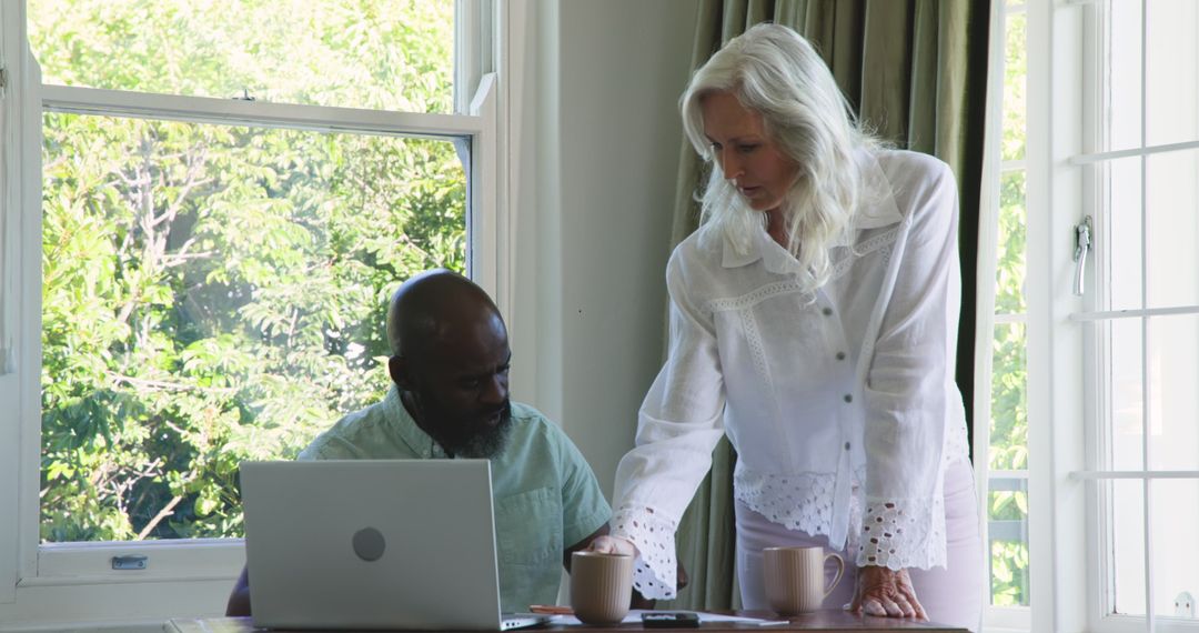 Senior Couple Planning Together Using Laptop at Sunlit Home Table