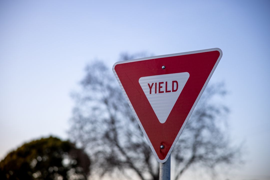 Triangle Yield Sign at Quiet Intersection with Blue Sky