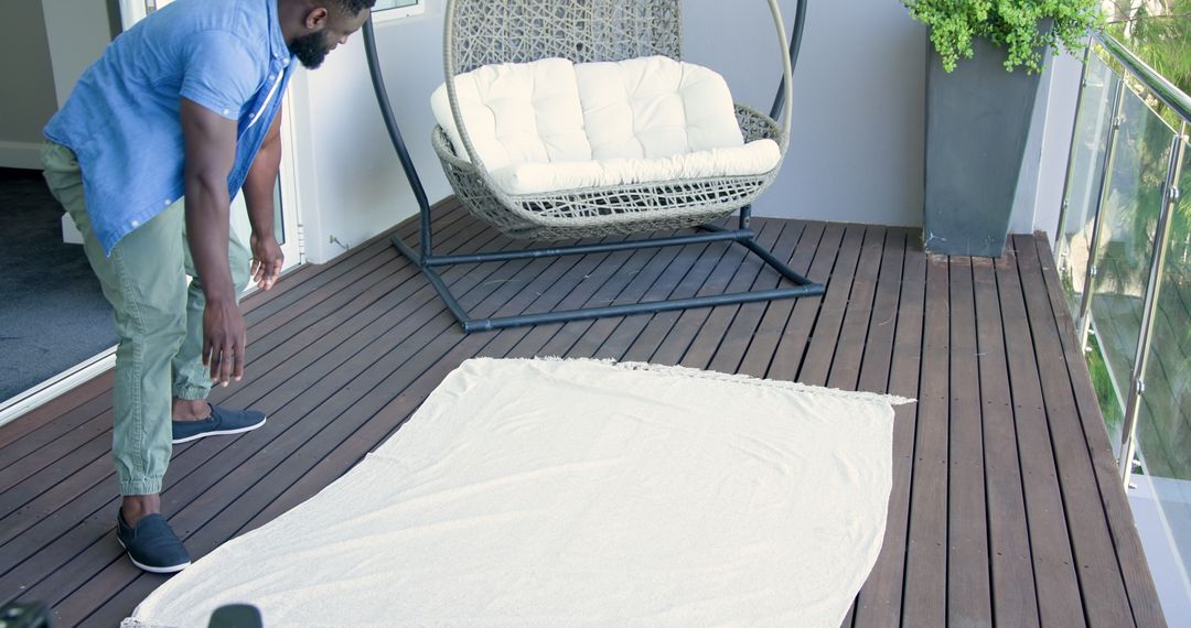 Man Arranging Blanket on Modern Balcony for Relaxation