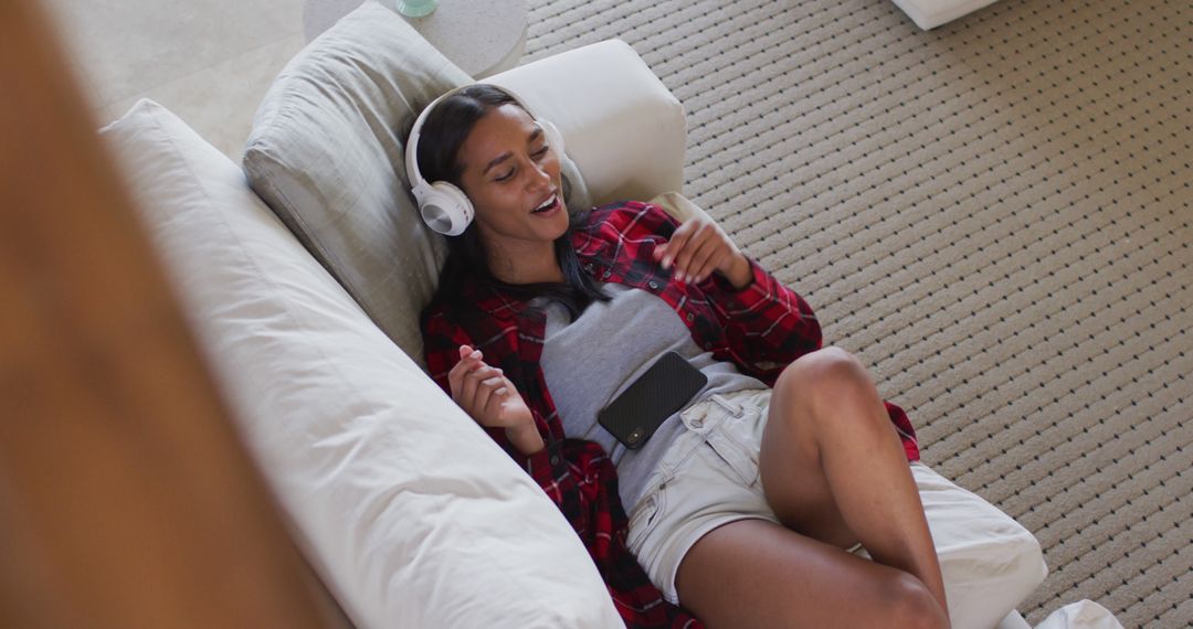 Relaxed Woman Listening to Music on Headphones Lounging on Sofa - Free Images, Stock Photos and Pictures on Pikwizard.com