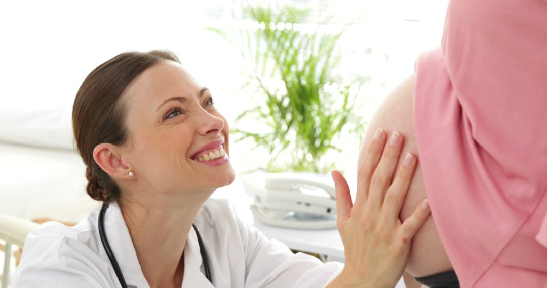 Smiling Doctor Examining Pregnant Woman's Belly in Clinic - Free Images, Stock Photos and Pictures on Pikwizard.com