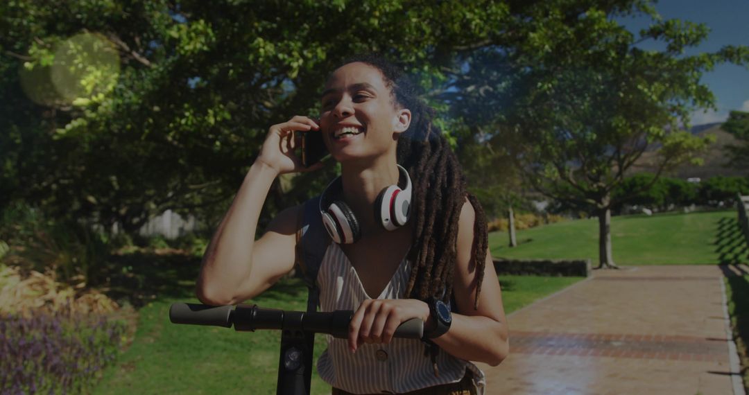 Woman with Dreadlocks on E-Scooter Talking on Smartphone in Park