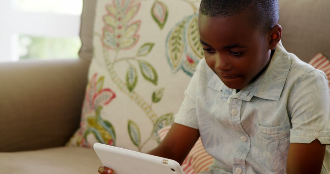 African American Child Using Tablet on Couch with Decorative Cushions - Free Images, Stock Photos and Pictures on Pikwizard.com