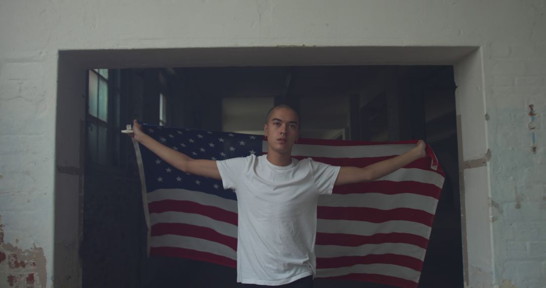 Young man holding American flag indoors - Free Images, Stock Photos and Pictures on Pikwizard.com