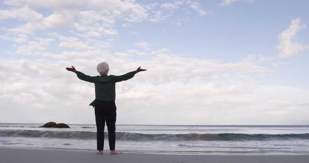 Senior Woman Enjoying Tranquil Beach View with Open Arms