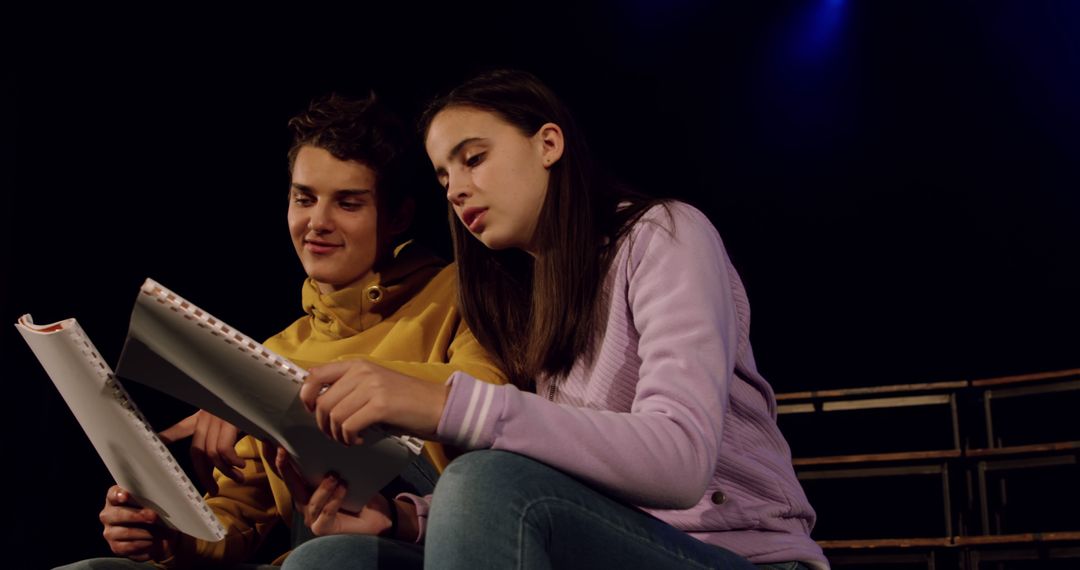 Two teenagers rehearsing lines in dark theatre - Free Images, Stock Photos and Pictures on Pikwizard.com