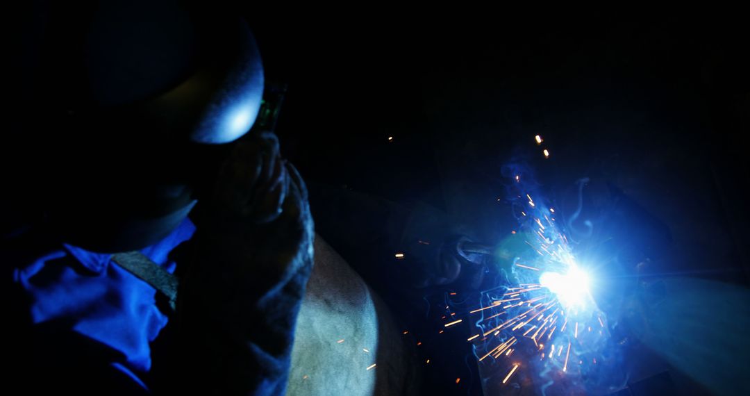 Welder Working With Bright Spark In Dark Workshop - Free Images, Stock Photos and Pictures on Pikwizard.com