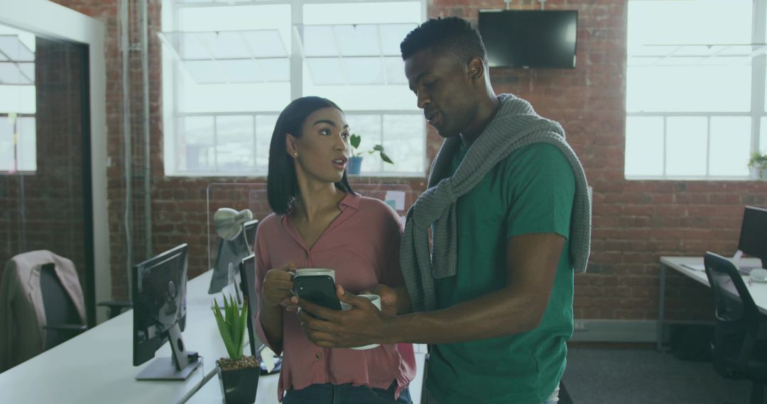 Coworkers Discussing Smartphone App in Modern Office