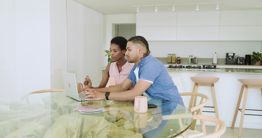 Diverse Couple Utilizing Laptop at Dining Table with Coffee Cups
