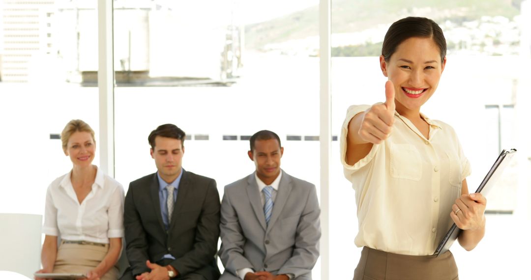 Confident Businesswoman Giving Thumbs Up in Front of Colleagues - Free Images, Stock Photos and Pictures on Pikwizard.com