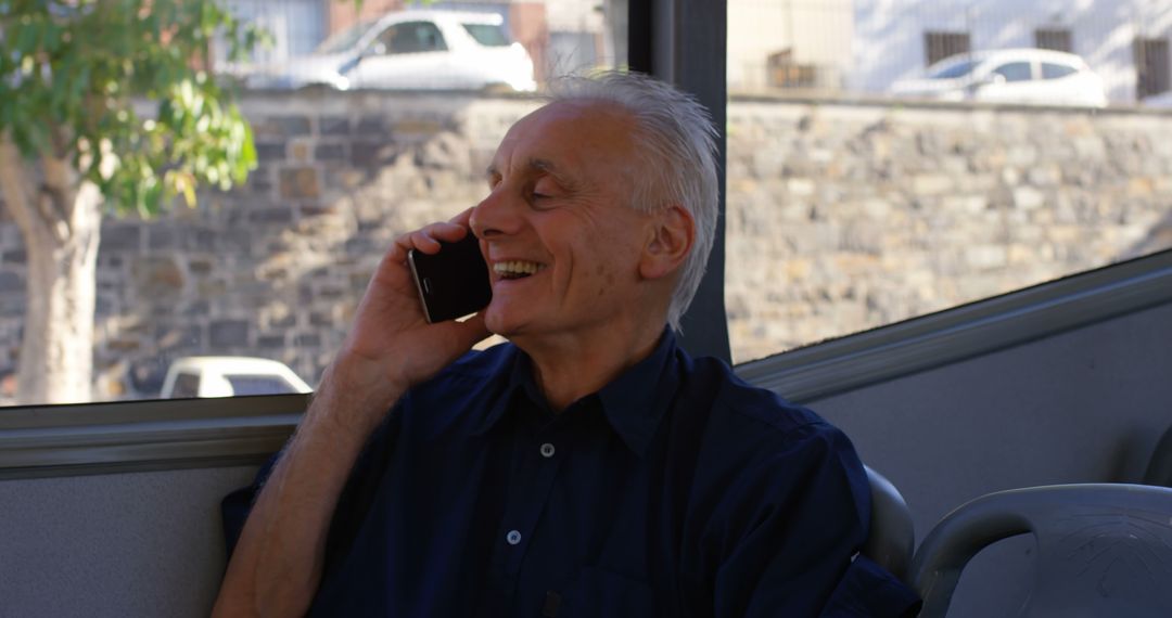 Elderly Man Smiling While Talking on Phone in Public Transportation - Free Images, Stock Photos and Pictures on Pikwizard.com