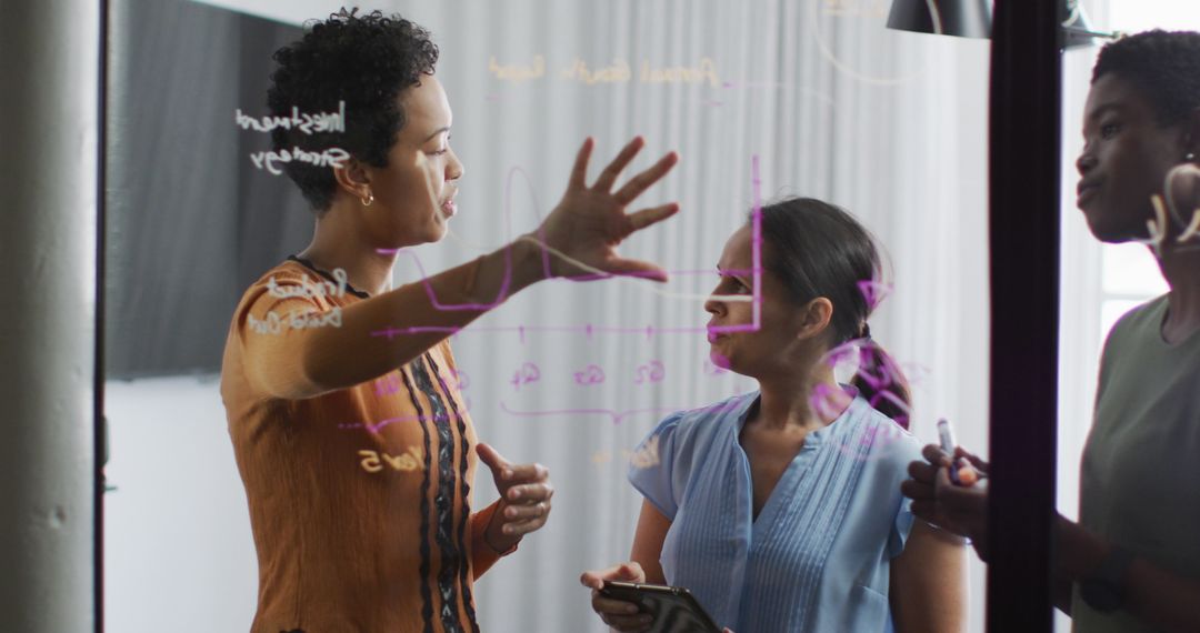 Businesswomen Collaborating on Ideas at Transparent Board