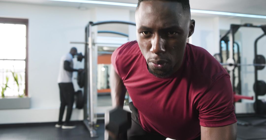 Focused Man Doing Dumbbell Rows at Modern Gym
