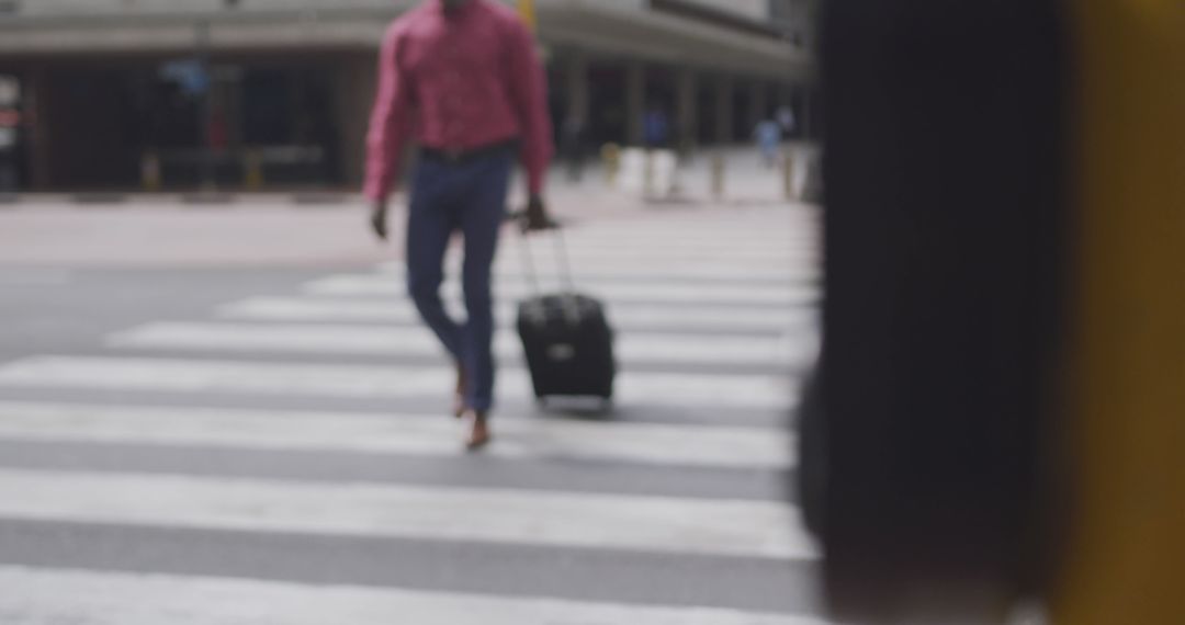 Man in Urban Crosswalk Pulling Suitcase on Wheels