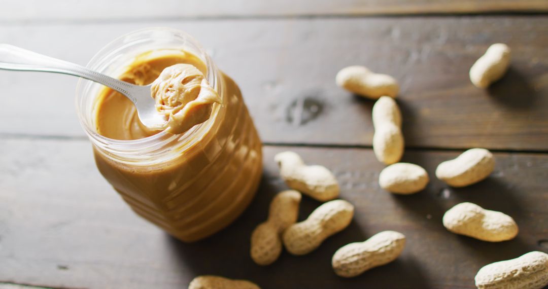Creamy Peanut Butter Jar and Peanuts on Wooden Table