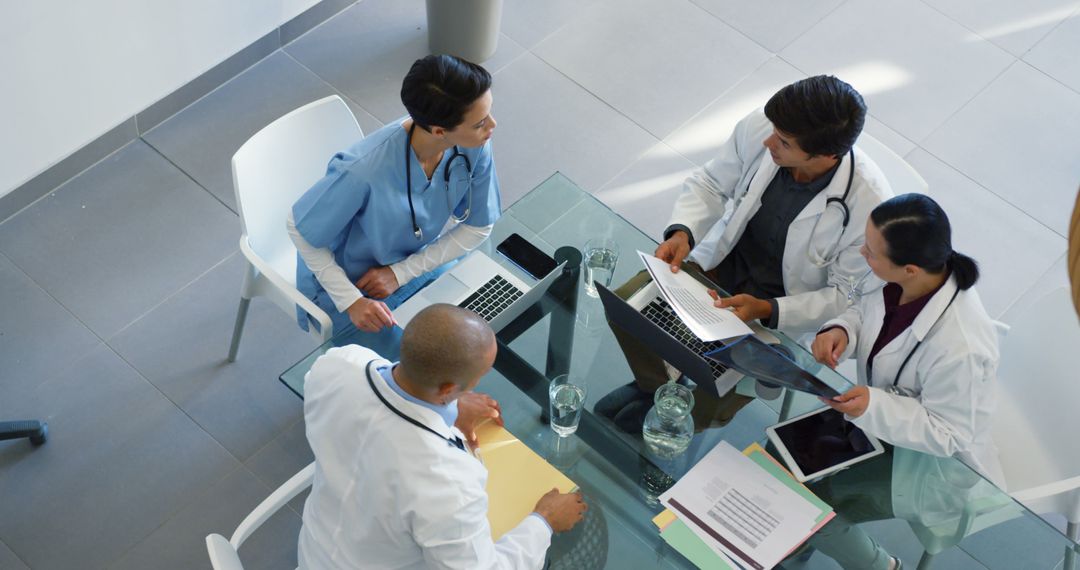 Medical Team Discussing Patient Reports at Glass Conference Table - Free Images, Stock Photos and Pictures on Pikwizard.com