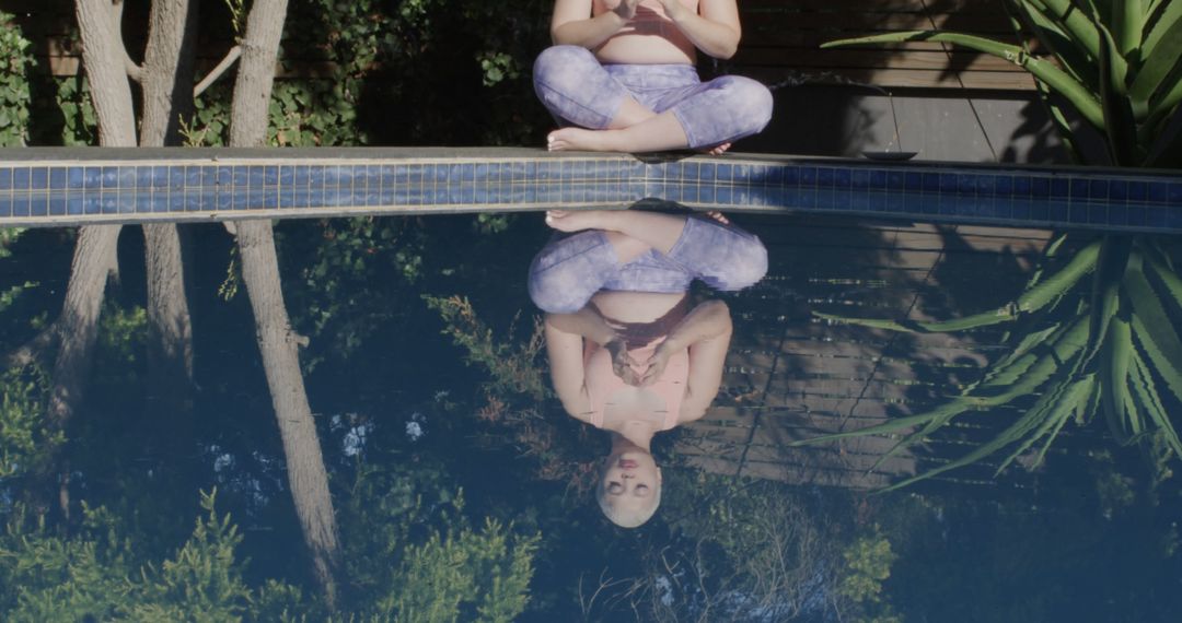 Woman Meditating by Pool with Reflection on Water - Free Images, Stock Photos and Pictures on Pikwizard.com