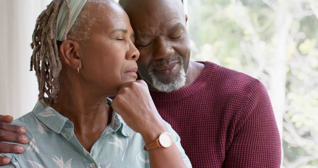 Content Senior Couple Embracing by Sunny Window