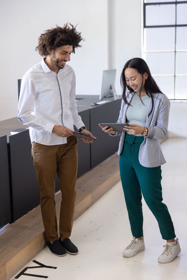 Diverse Coworkers in Modern Office Reviewing Plans on Tablets