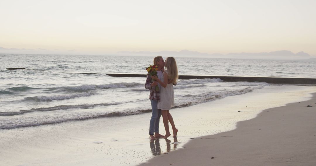 Romantic caucasian couple embracing and kissing on beach at sunset - Free Images, Stock Photos and Pictures on Pikwizard.com