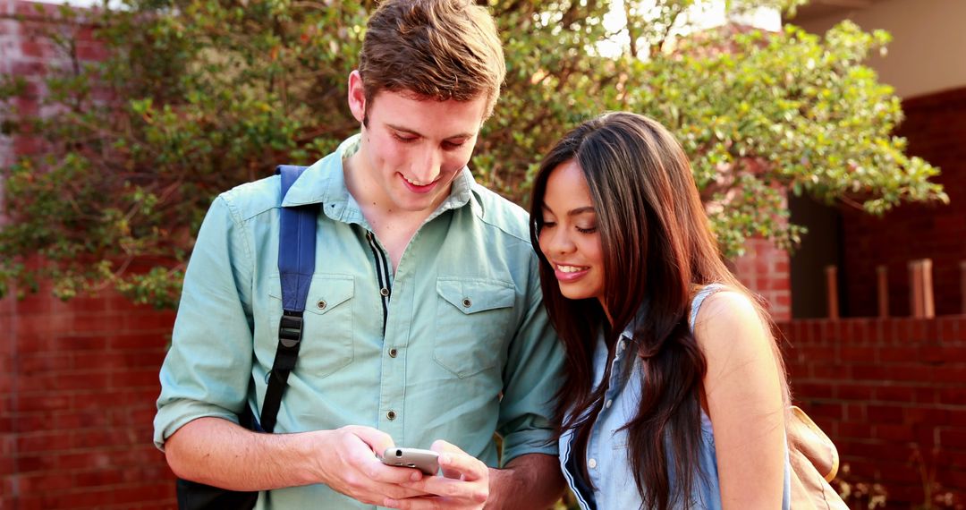 Smiling Students Using Smartphone Outdoors on Campus - Free Images, Stock Photos and Pictures on Pikwizard.com