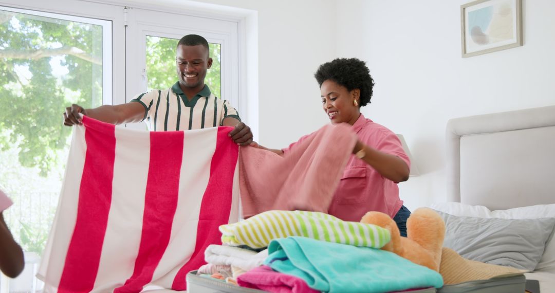 Happy Couple Folding Colorful Towels Together at Home