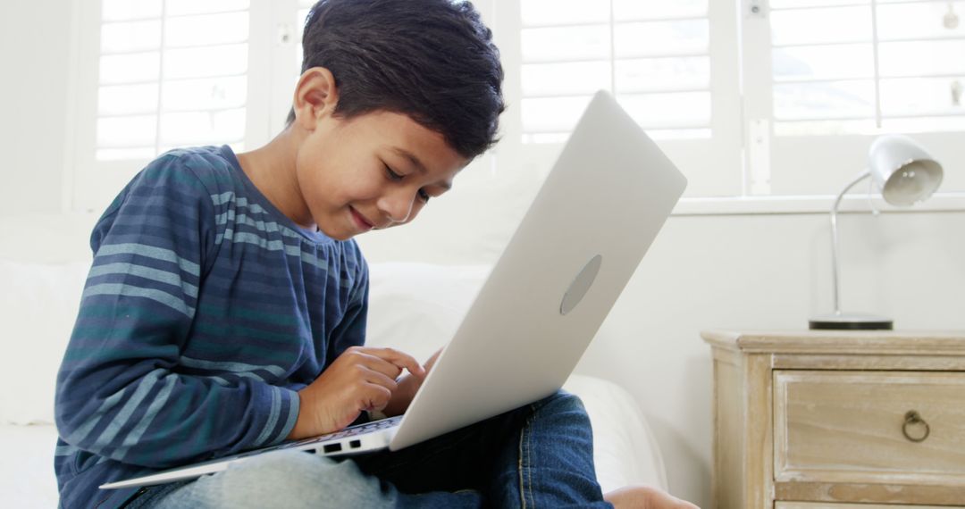 Young Boy Using Laptop on Bed - Free Images, Stock Photos and Pictures on Pikwizard.com